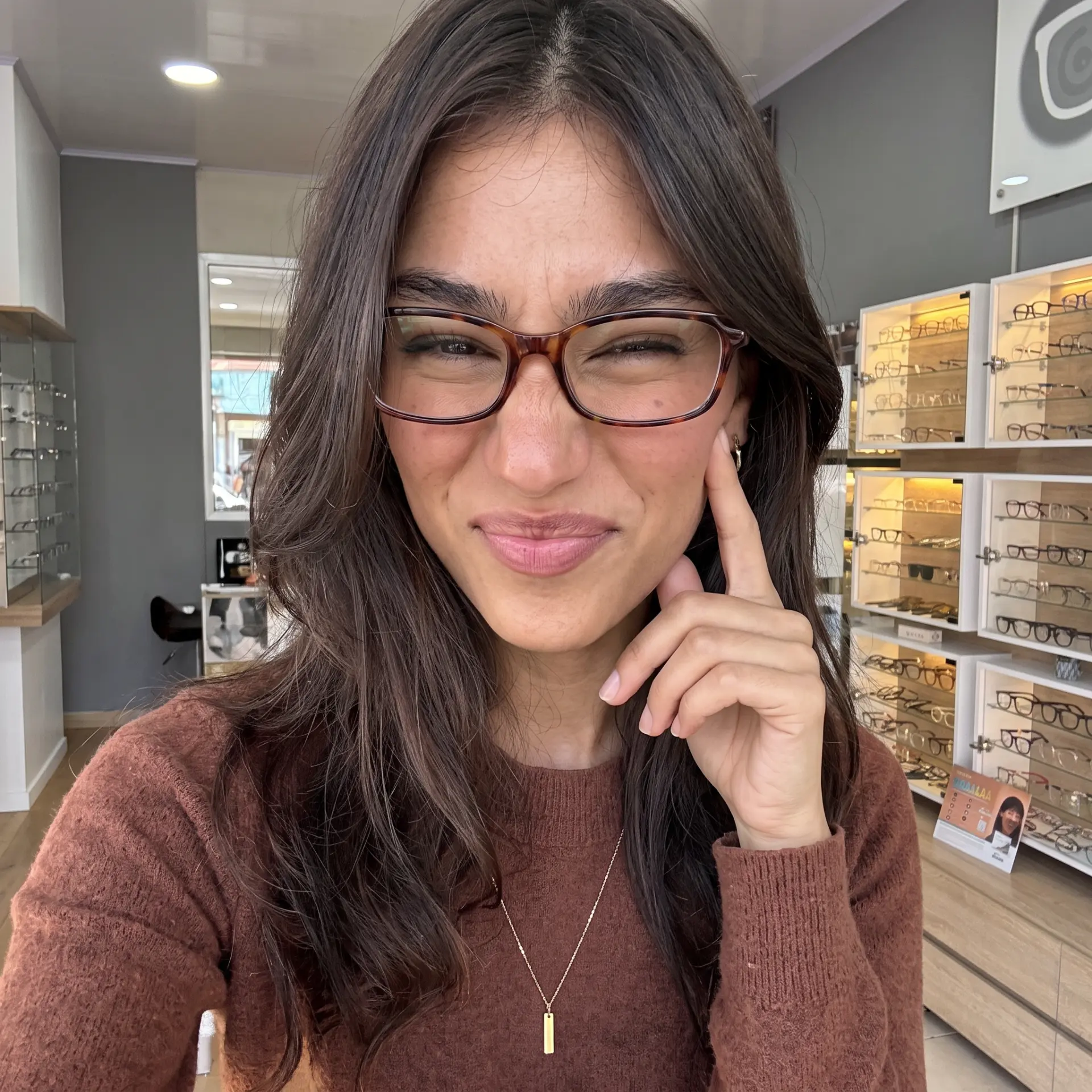 Modelo usando gafas frente a la exhibición de monturas de la tienda
